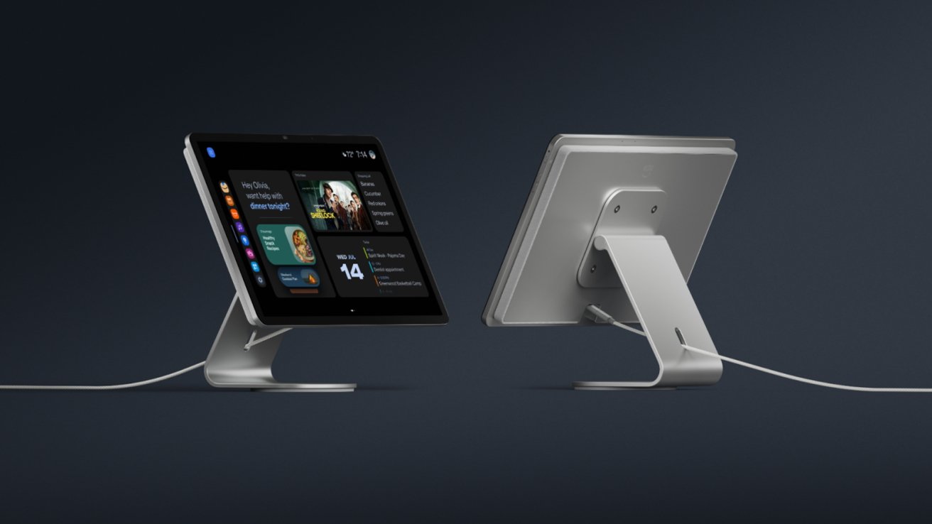 Two sleek tablet-like smart displays on metallic stands, one showing a colorful home screen, the other turned away, both connected with white power cables against a dark background