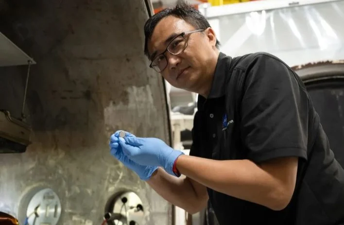 Yi Lin, SPEARS testing and research lead, holds a coin-cell battery after testing - Image: NASA/Hill — Picture from hothardware.com