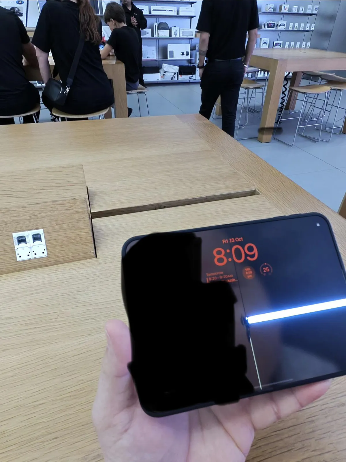 u/Midnight_Slump, in an Apple Store. He said the screen cracked within six hours and fewer than 20 opens. A black shape covers the left of the photo. The white line on the right is the screen.