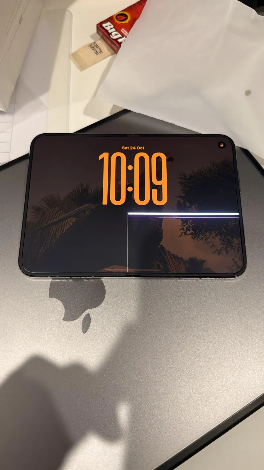 u/scary_duck23 said the inner display cracked in under 24 hours. The lock screen reads Saturday, October 24. A bright line sits on the right of the crease, with a thin green line at the fold. 9to5Mac credited this post for its top image.
